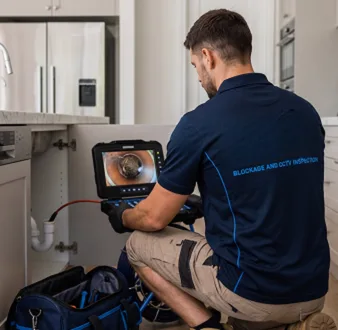 Plumber clearing a blocked toilet in a Strathfield bathroom